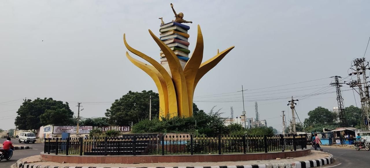 The Kota Book Sculpture on its roundabout — tall golden leaf forms rising around a stack of coloured books, with a figure on top