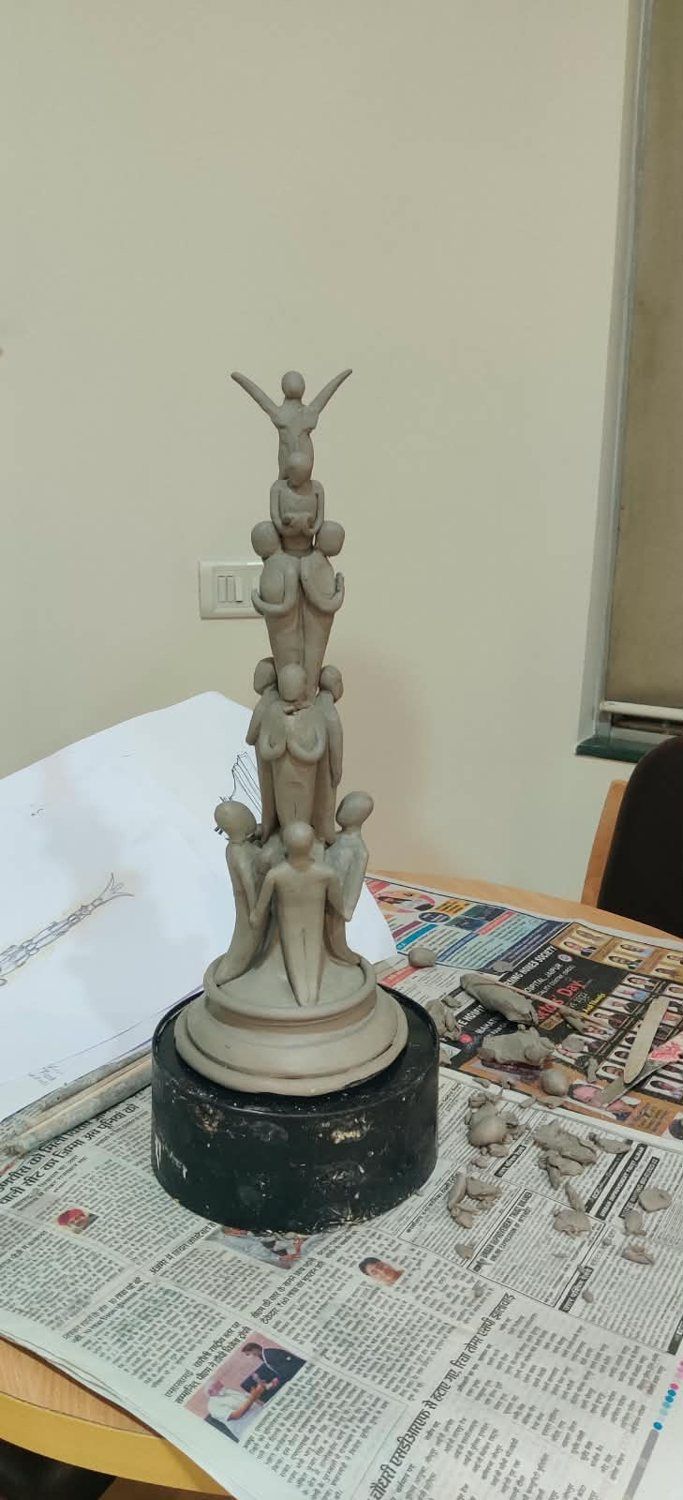 Clay maquette of the stacked-figure sculpture on a turntable