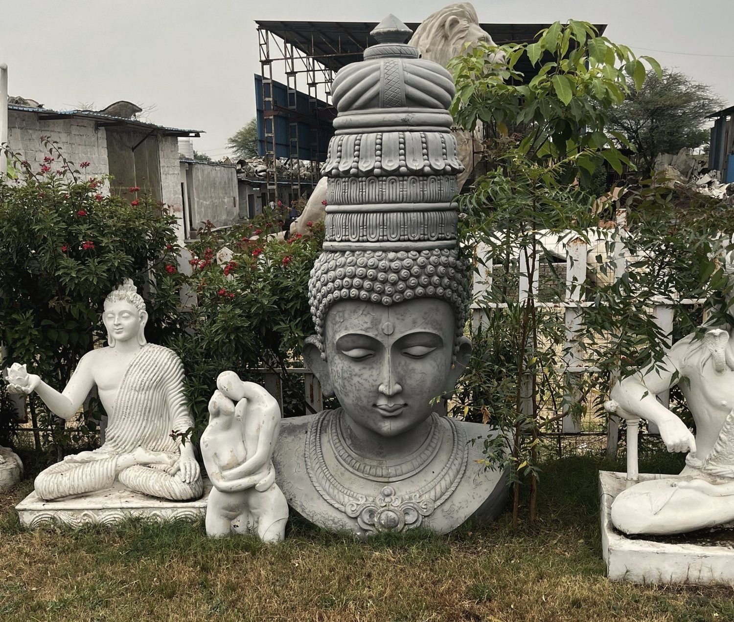 Studio yard with a large crowned stone bust surrounded by white seated figures